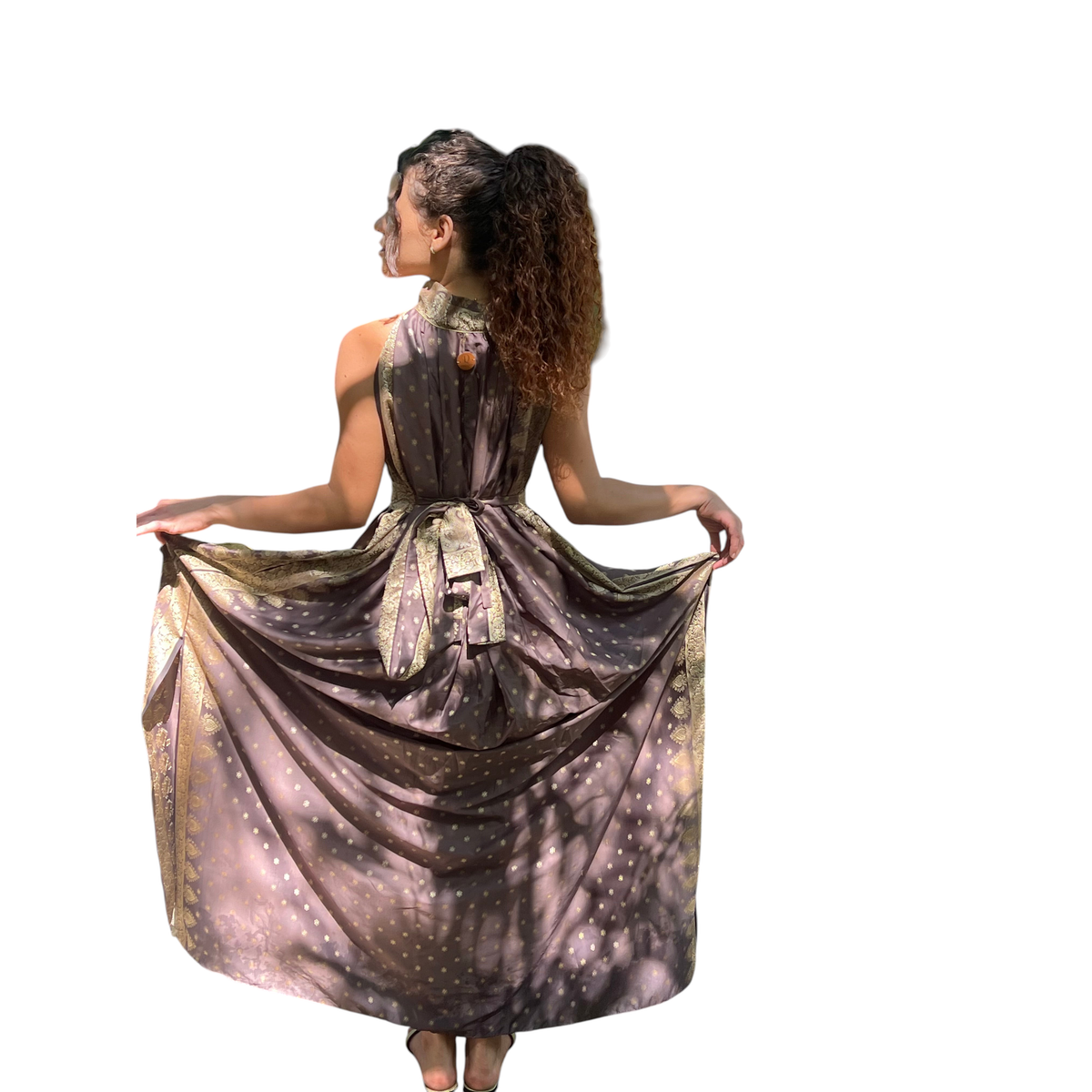 Vestido longo Dani Levine em seda chocolate com detalhes dourados, decote alto e saia fluida em ambiente tropical.