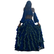 Conjunto Dani Levine Jardin Bleu com top drapeado azul real e saia longa de babados em tons de azul e sálvia ao ar livre