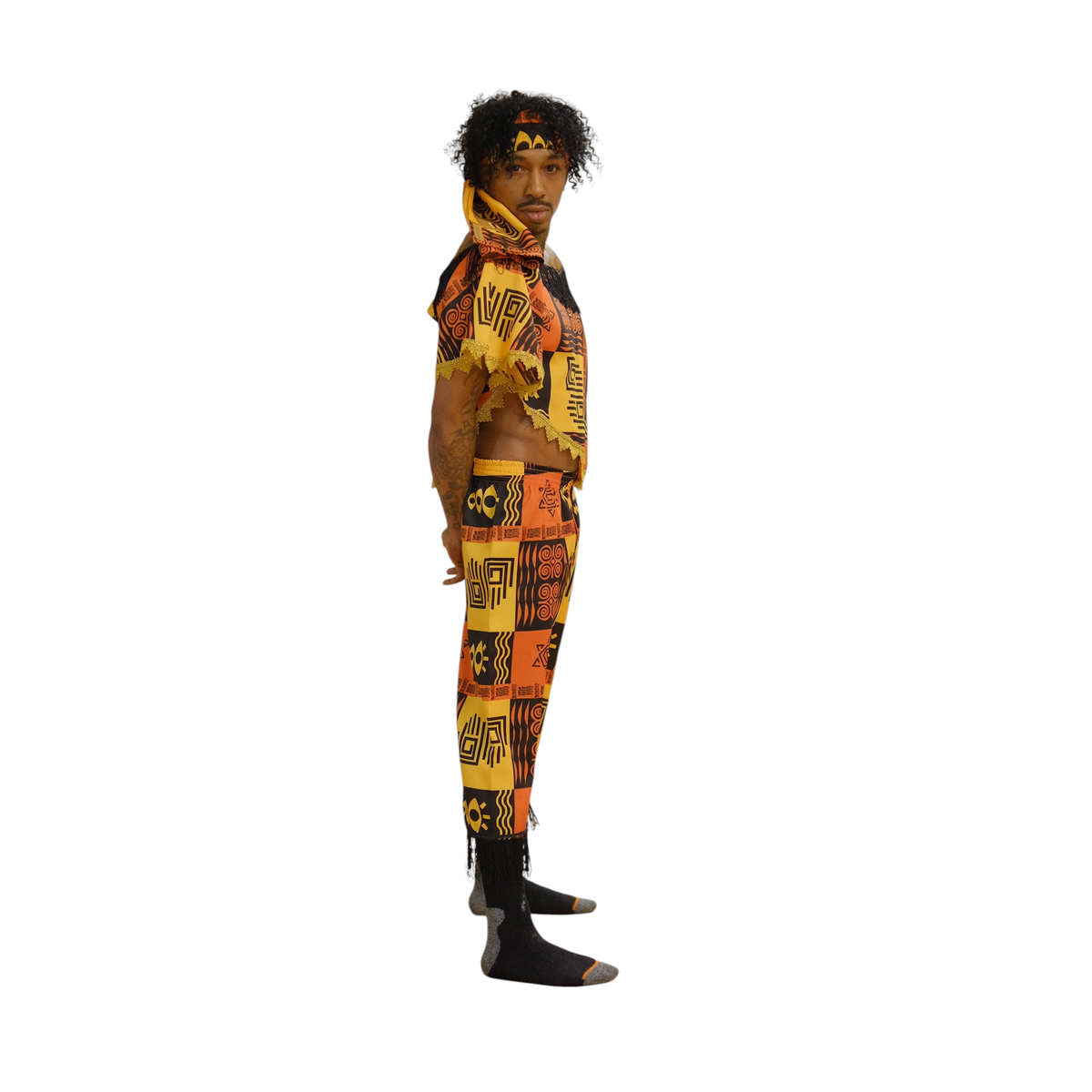 Modelo vestindo conjunto Dani Levine Heritage Rhythm com estampa geométrica laranja, dourada e preta e detalhes de franja