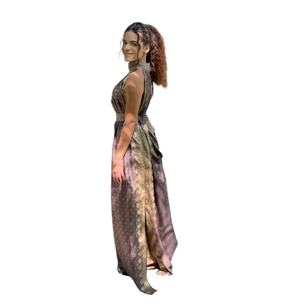 Modelo usando vestido longo Dani Levine marrom com detalhes dourados, gola alta e saia fluida em ambiente externo.