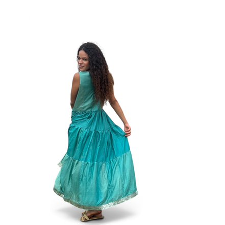Modelo usando vestido midi Dani Levine de linho turquesa com saia em camadas e detalhes metálicos em fundo colonial
