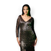 Modelo vestindo vestido longo Dani Levine bronze com brilho metálico, decote em V e mangas longas transparentes.