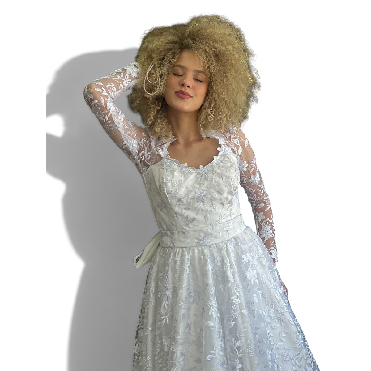 Modelo com vestido de noiva Dani Levine 2 em 1, renda floral branca, mangas longas transparentes e decote coração.
